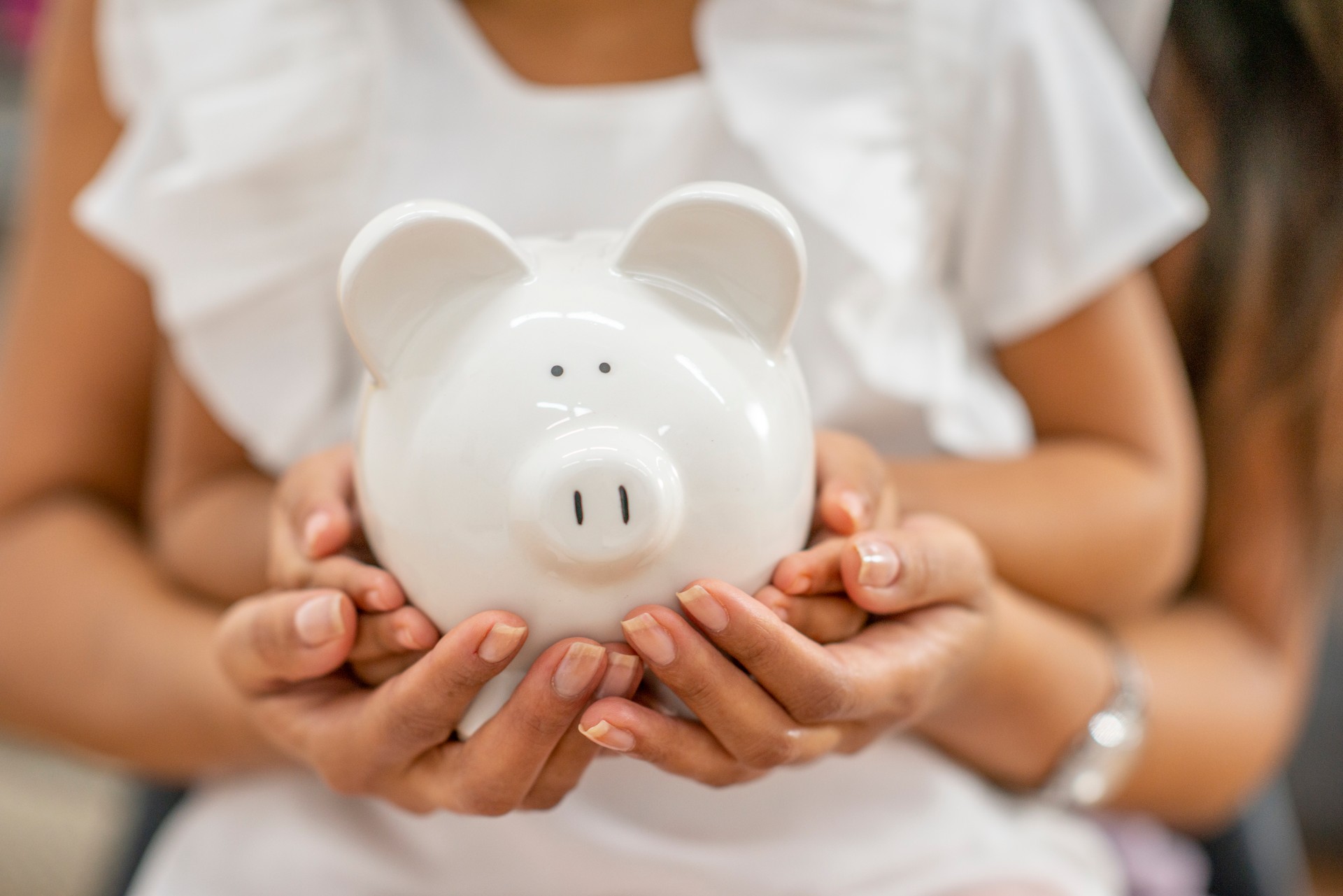 Child and mother holding white piggybank